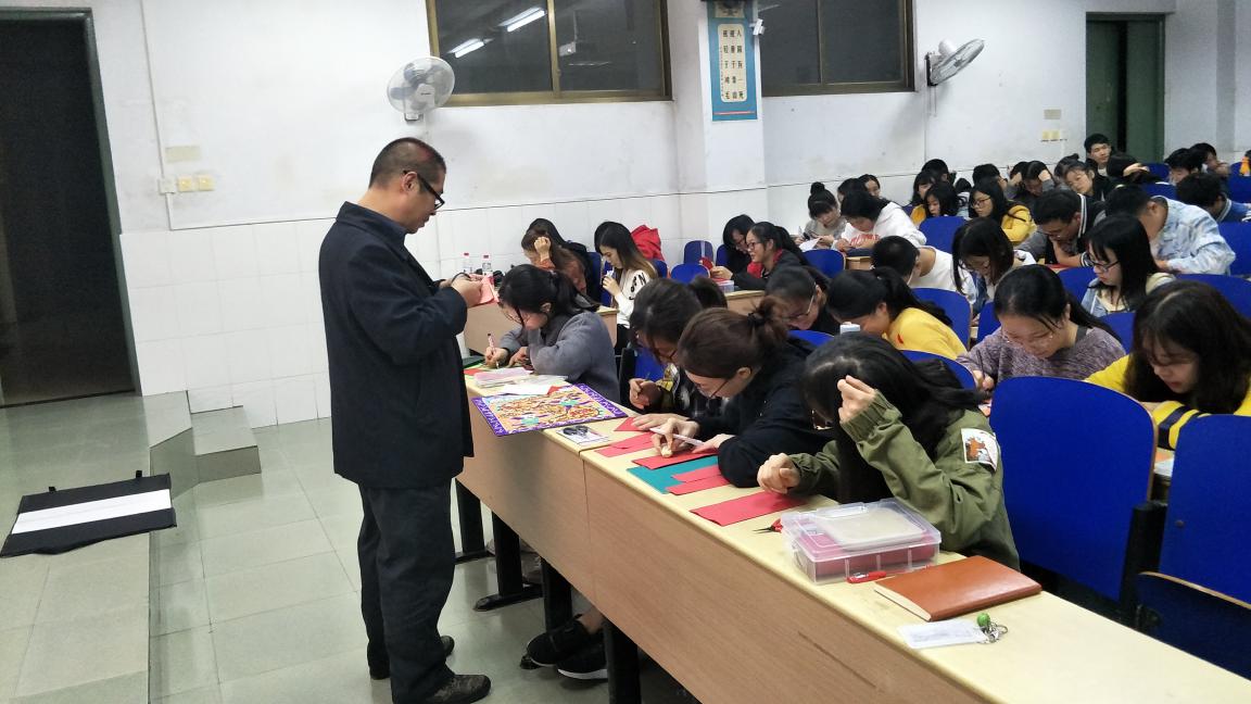 图为谢志平老师指导学生剪纸